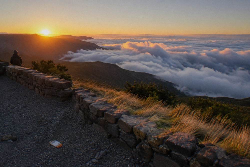 A sea of clouds filling the valleys below the clear Haleakala summit at sunrise